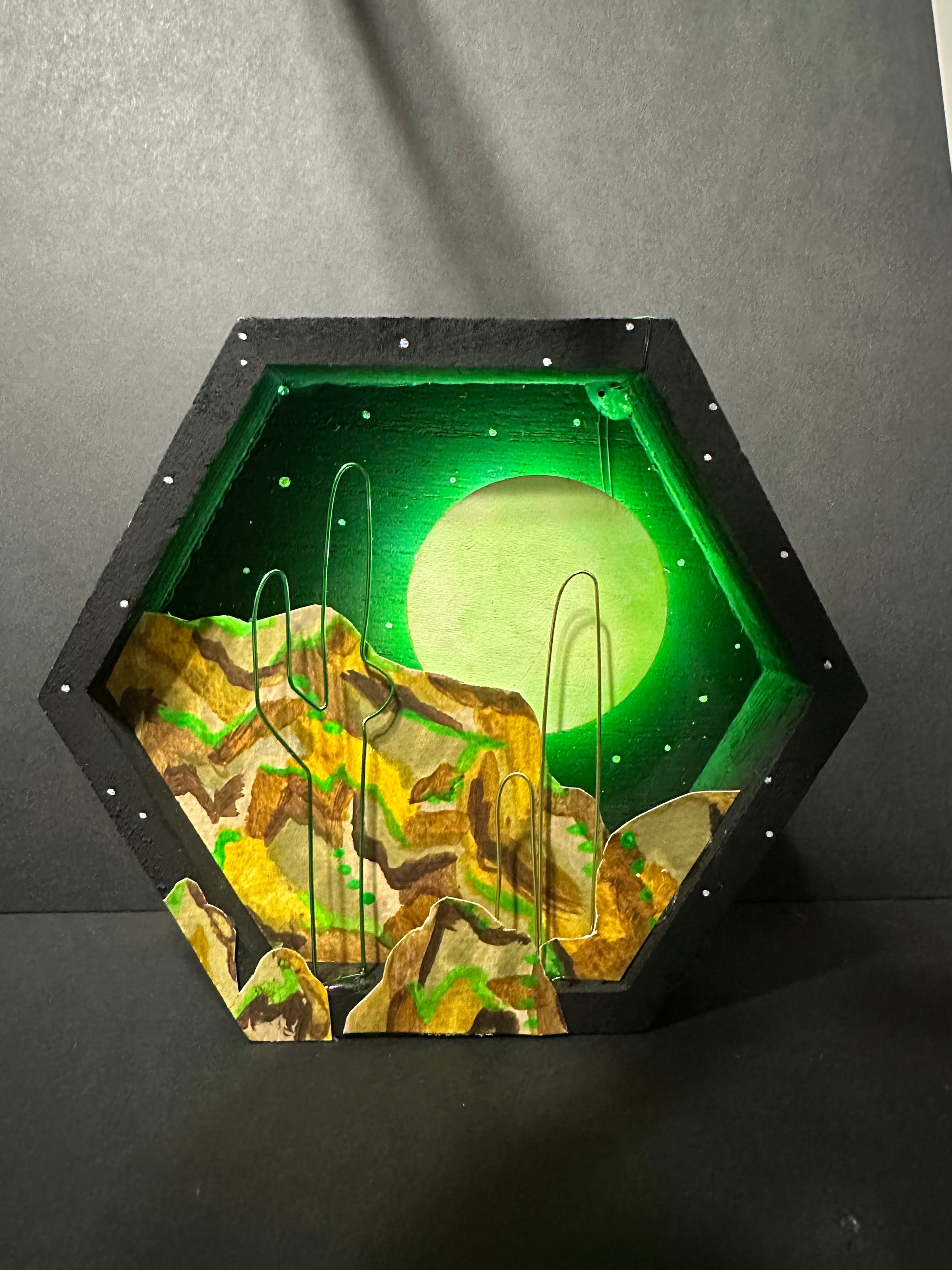 Hexagonal wood frame with a stylized depiction of an Arizona desert with a  glowing moon on a dark background